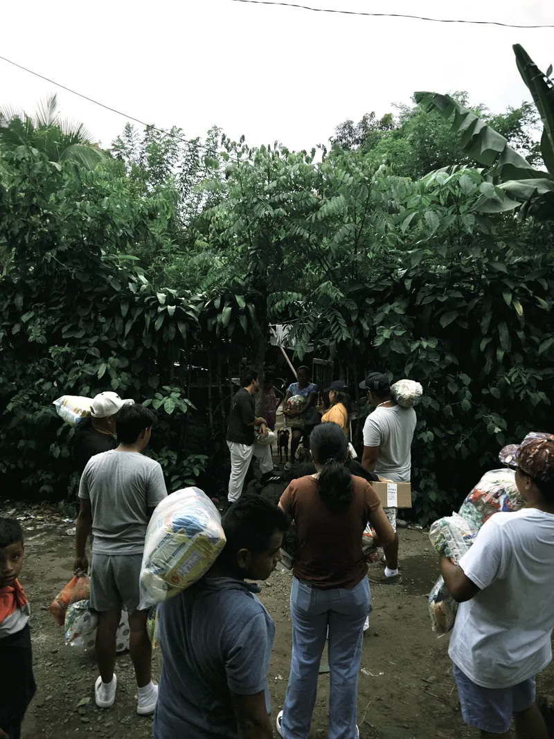Grupo caminando entre la vegetación con bolsas de víveres